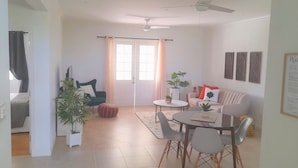 A spacious living area with a dining table, a sofa, and a ceiling fan.