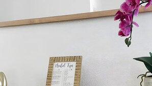 A glass-top desk with a woven wooden side panel, a framed 'Useful Tips' sign, and a potted orchid plant.