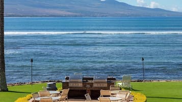 Un espace extérieur aménagé avec un barbecue et des chaises, donnant sur un plan d’eau.