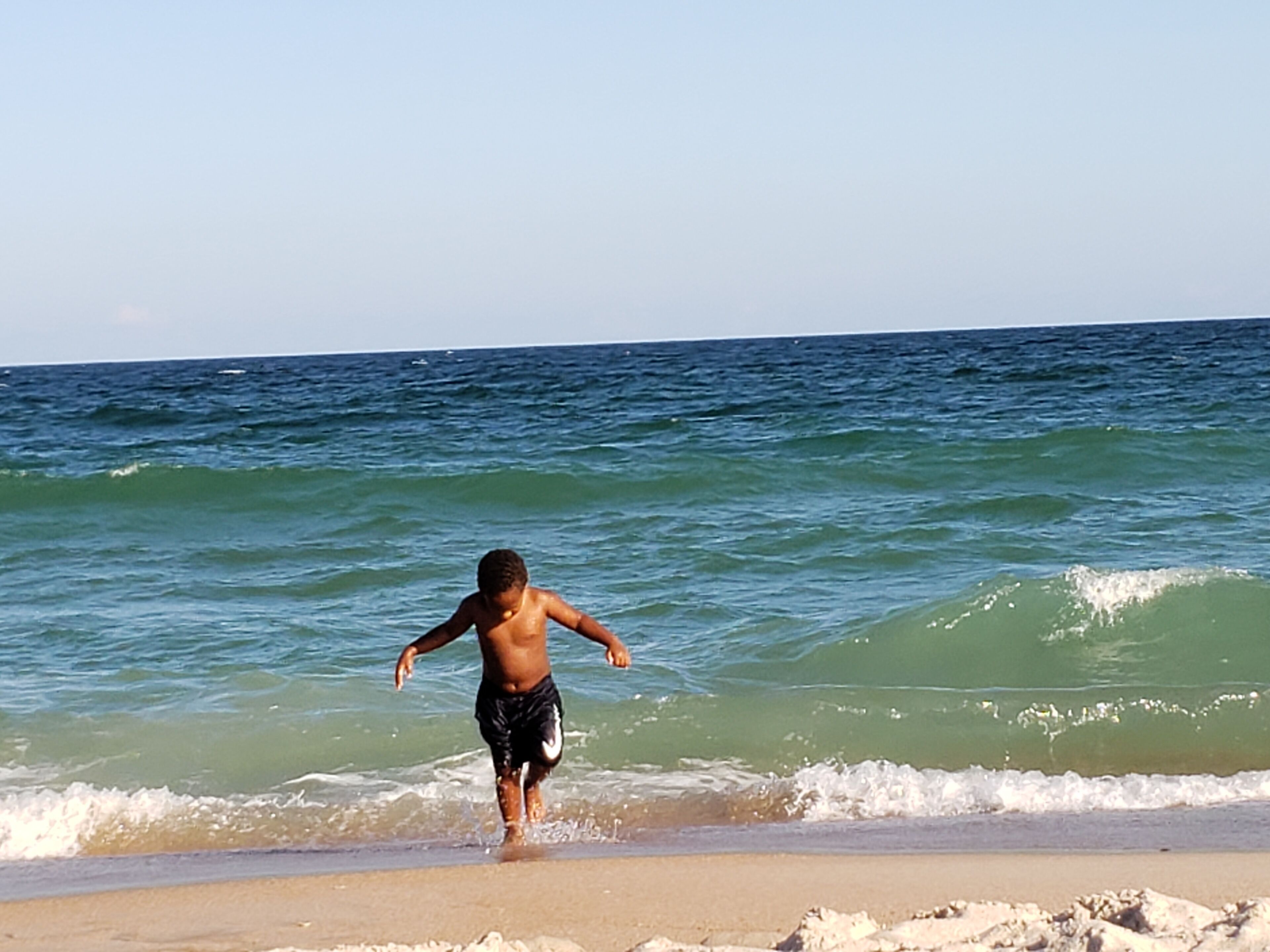 Escena de playa con un niño jugando en el agua.