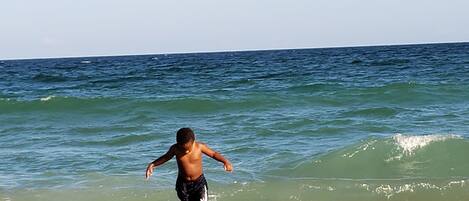 Escena de playa con un niño jugando en el agua.