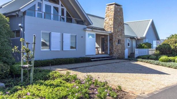 A modern two-story house with a stone chimney, large windows, and a well-maintained garden. - Sunridge Aan Zee | Luxury beach villa Onrus beach (Onrus)