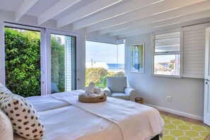 Une chambre à coucher avec un lit, une chaise, une fenêtre donnant sur un paysage et un tableau accroché au mur.