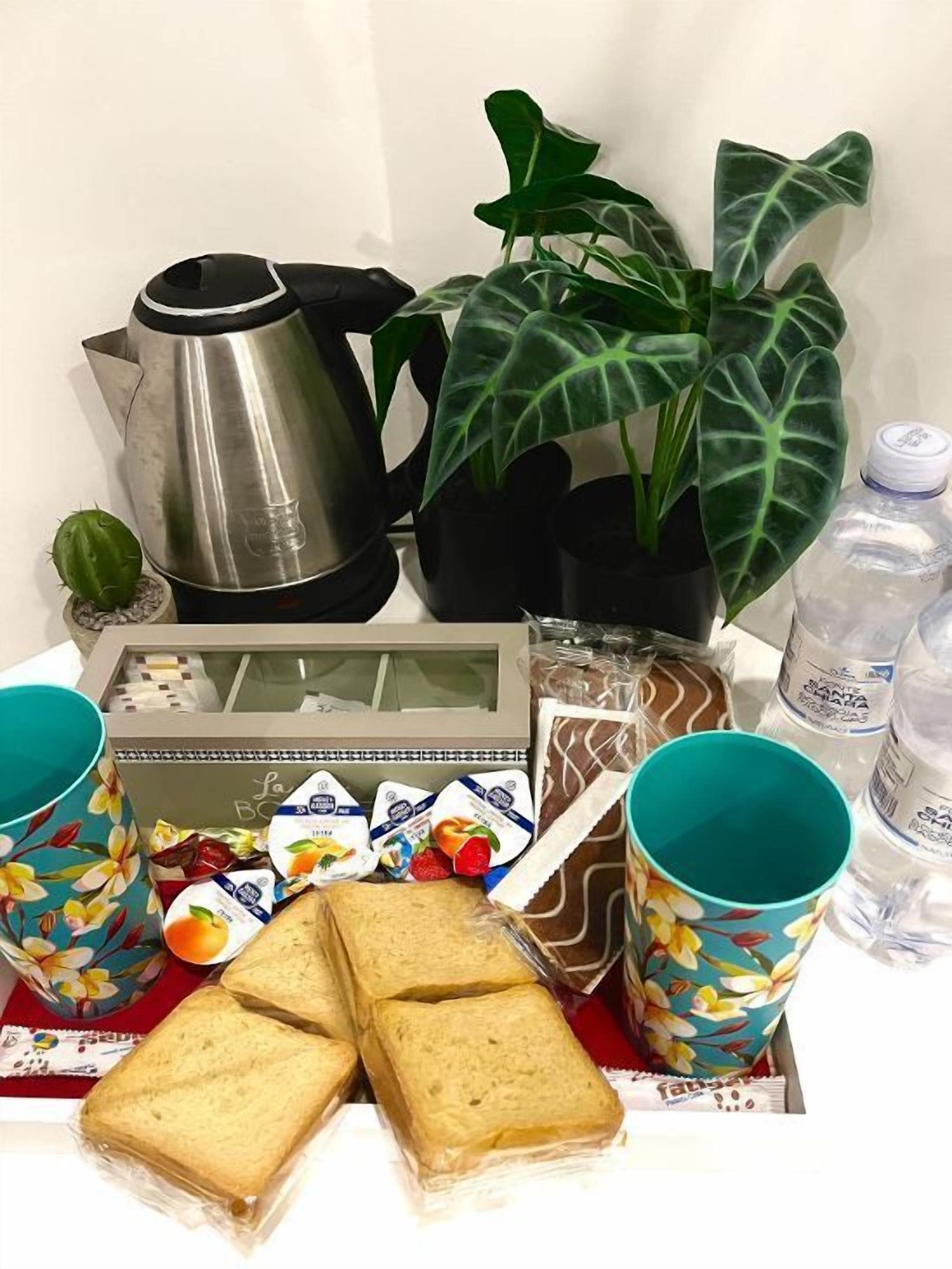 En frukostuppsättning med en kaffebryggare, en växt, en fruktkorg och förpackade livsmedel.