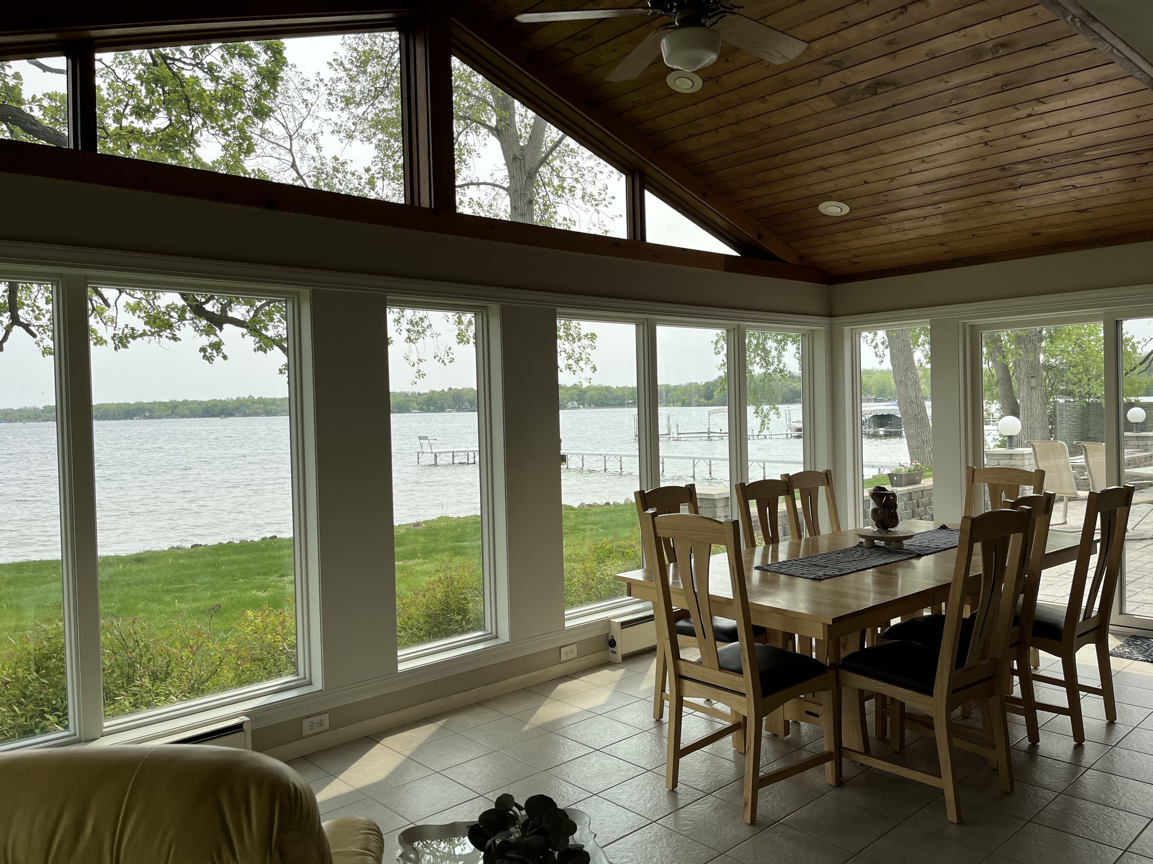 Un espace repas avec vue sur un lac, un plafond en bois et de grandes fenêtres.