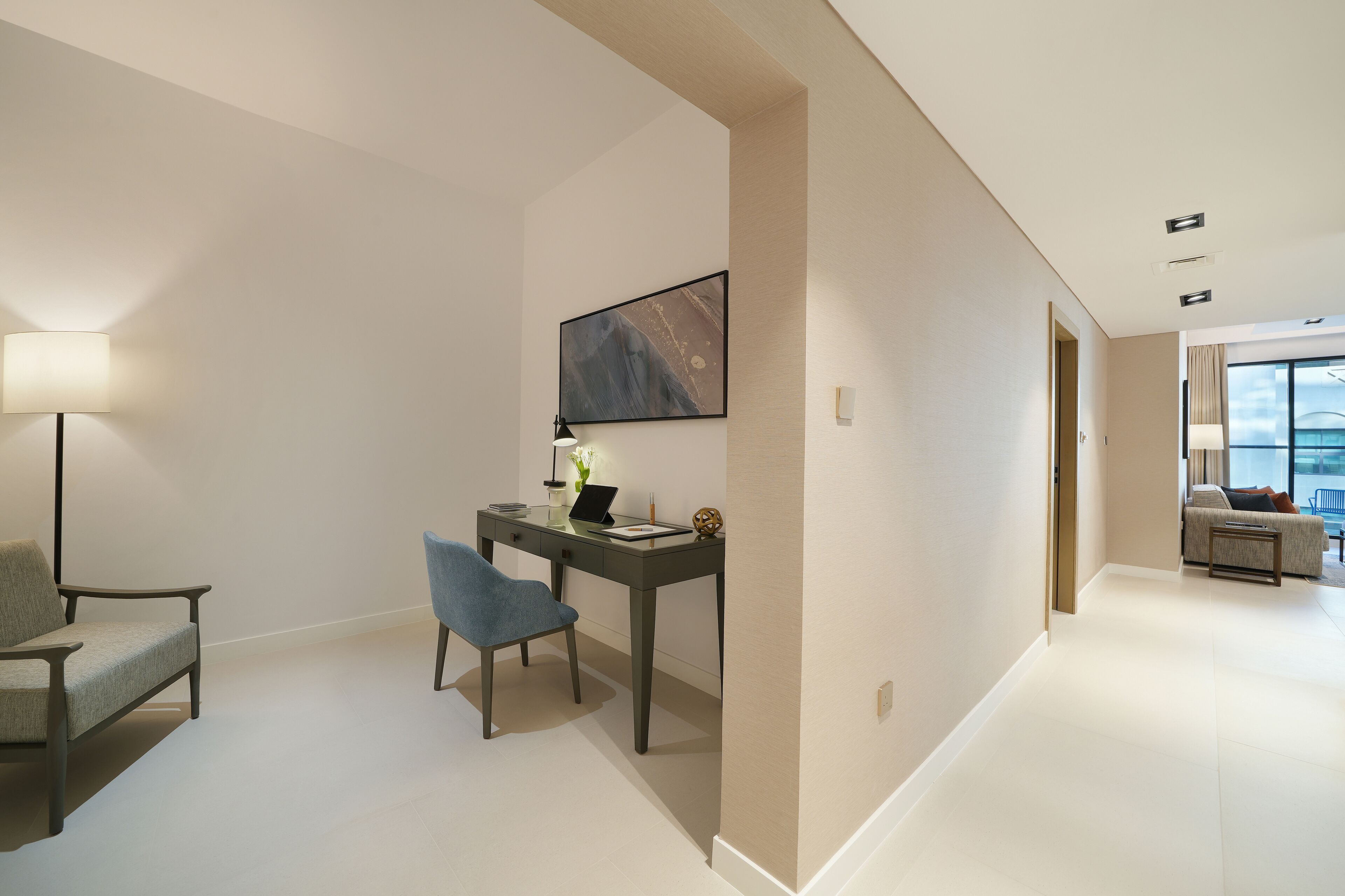 A modern hotel room with a desk, chair, and a large window.