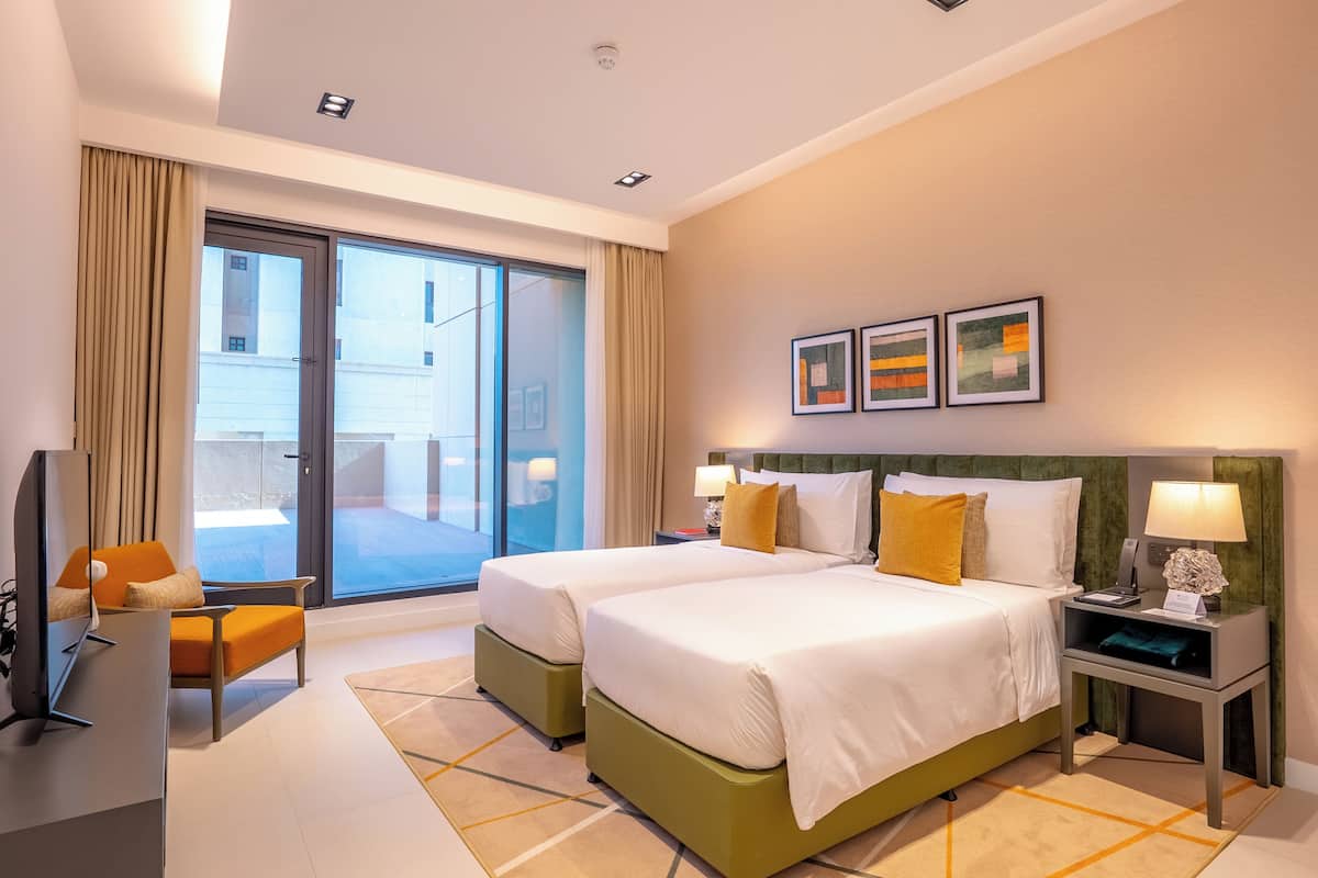 Une chambre d’hôtel avec deux lits, une télévision, un bureau et une vue sur l’extérieur.