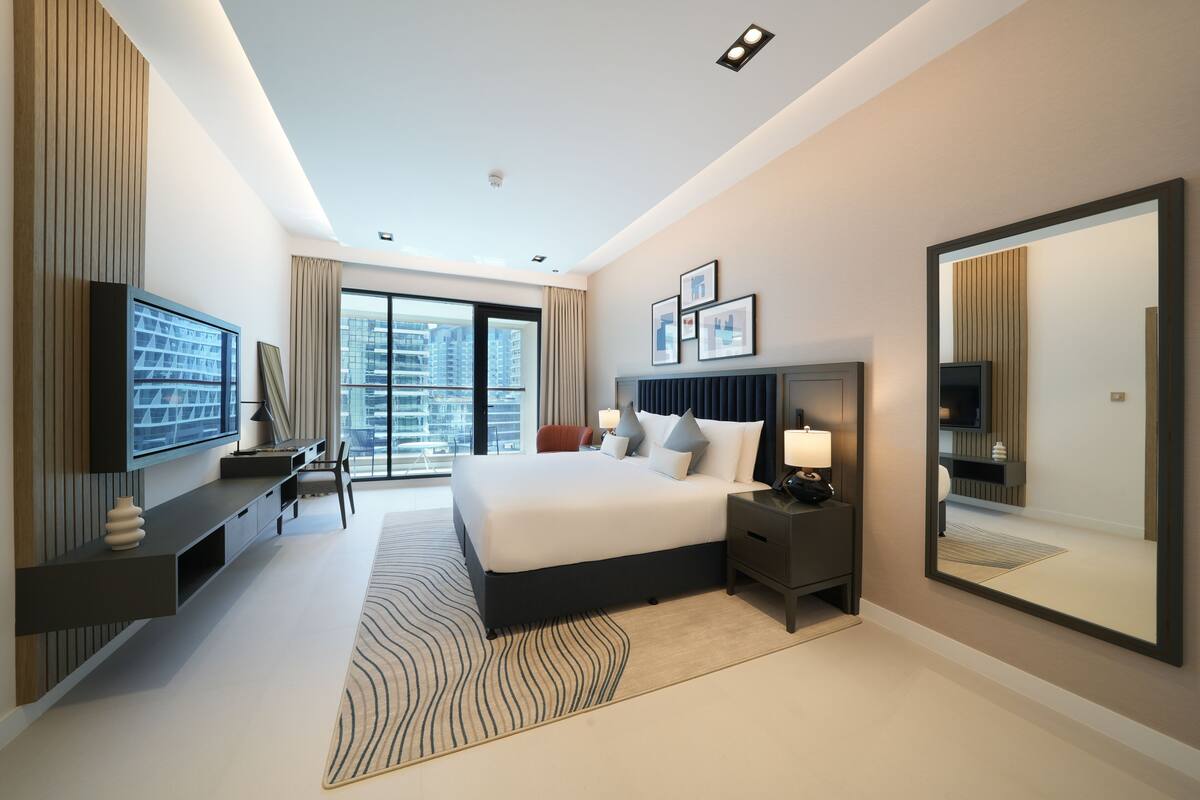Une chambre d’hôtel moderne dotée d’un grand lit, d’une télévision, d’un bureau et offrant une vue sur la ville.
