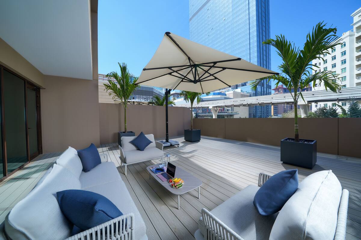 Un espace de détente extérieur moderne, comprenant un canapé, une table basse et un parasol.