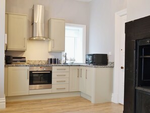 A kitchen with white cabinets, a Bosch oven, a microwave, and a stainless steel range hood.