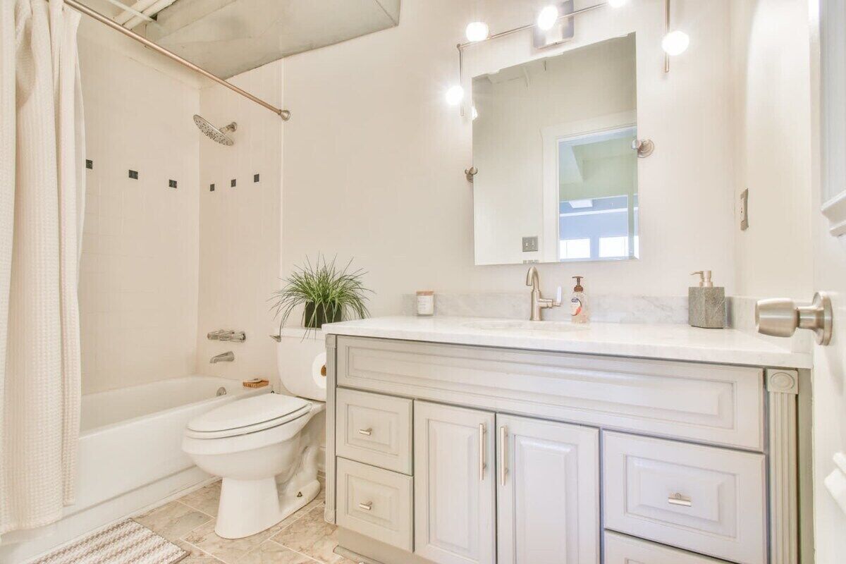 A bathroom with a bathtub, toilet, and vanity with drawers.