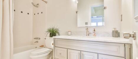 A bathroom with a bathtub, toilet, and vanity with drawers.