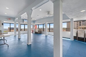 A spacious indoor area with large windows, a ceiling fan, and a Coca-Cola banner.