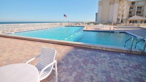 A swimming pool with lounge chairs and a view of the ocean. - 🌴Ocean View Condo on No-Drive Beach-Castle Reef 312🌴 (New Smyrna Beach)