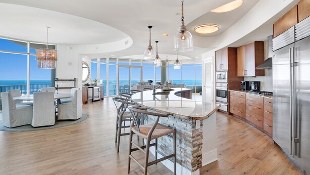 A spacious kitchen with a large island, modern appliances, and a view of the ocean. - Turquoise Place C1501 | Gorgeous Updates! Oversized, hot tub/grill on deck, huge slide for kids! (Orange Beach)