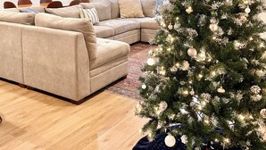 A modern living room with a beige sectional sofa, a Christmas tree, and a dining area with a table and chairs. - Hot Tub, Breakfast, and ideally located near Olympic National Park (Forks)