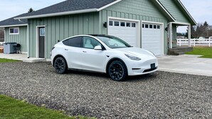A white Tesla parked in front of a light green building with a garage. - Hot Tub, Breakfast, and ideally located near Olympic National Park (Forks)