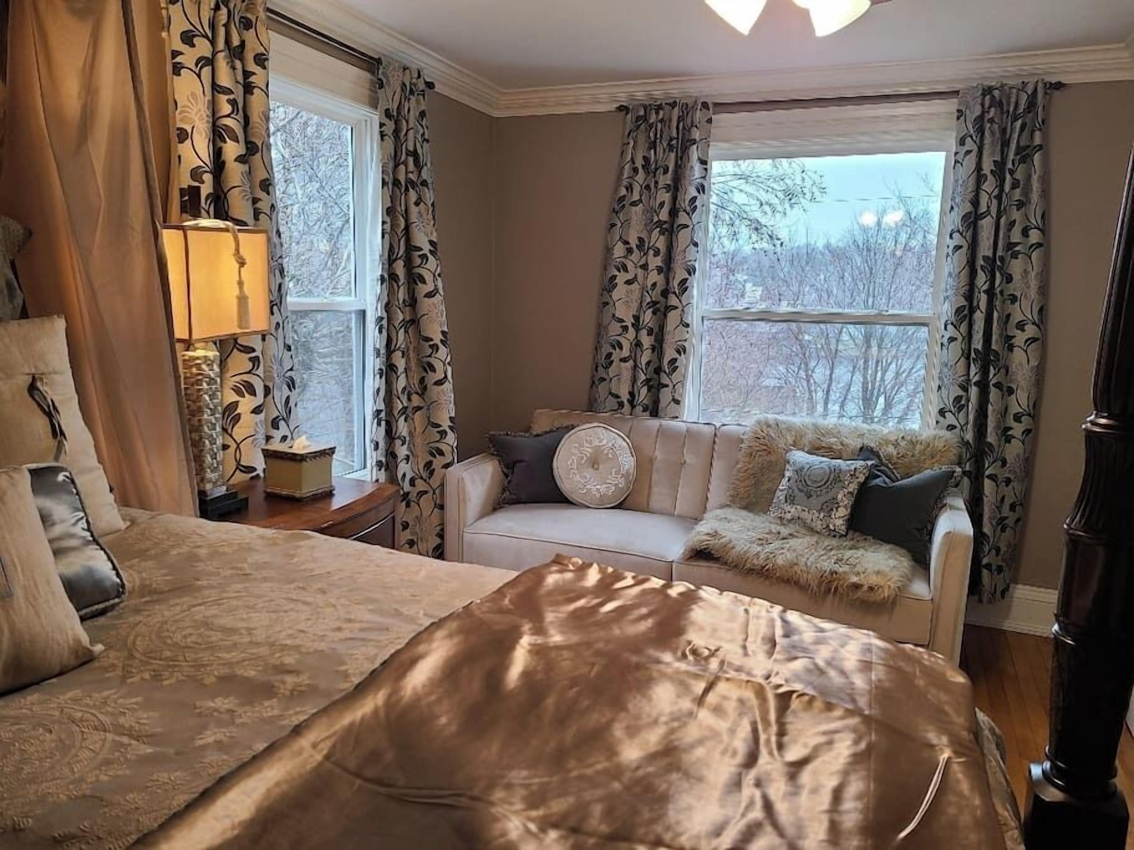 Une chambre avec un grand lit, un canapé et une fenêtre avec des rideaux.
