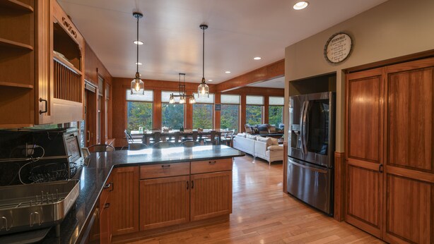 A spacious kitchen with wooden cabinets, a large island, stainless steel appliances, and pendant lighting. - Babcock Lake Luxury Retreat: Direct Waterfront, Deck & Huge Game Room (Petersburgh)
