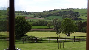 Une vue d’un paysage verdoyant avec des collines ondulantes, des arbres et une clôture en bois.