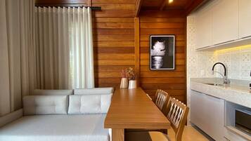 Una sala de estar moderna con techo de madera, un sofá, una mesa de comedor y una zona de cocina.