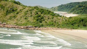 A coastal landscape with a beach, waves, and green hills. - Ilha do Mel Lodges (Paranaguá)