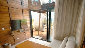 A modern living room with a wooden dining table, a sofa, and a TV on the wall. - Ilha do Mel Lodges (Paranaguá)