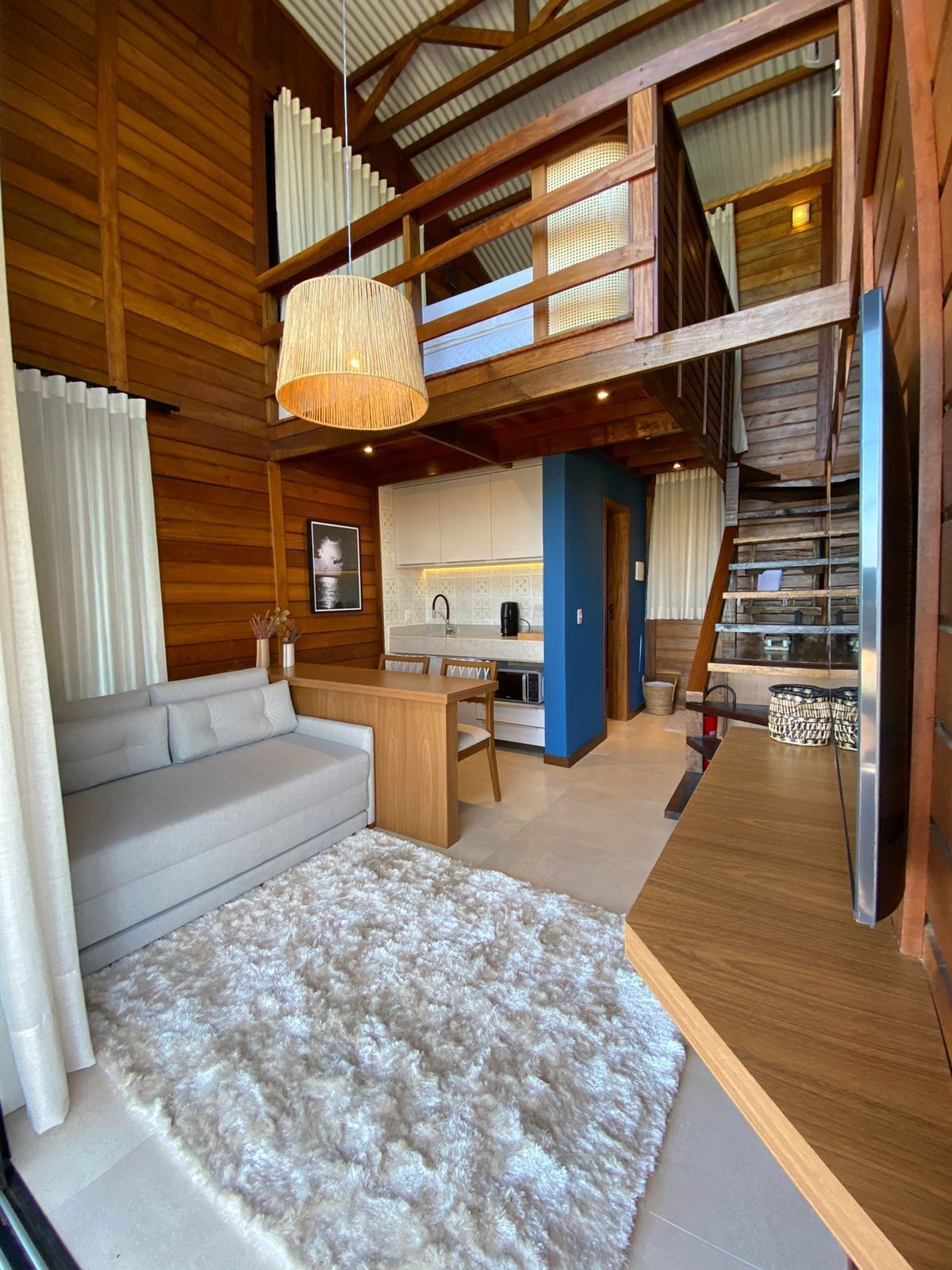Un intérieur moderne comprenant un canapé, un coin repas, une cuisine et un escalier.