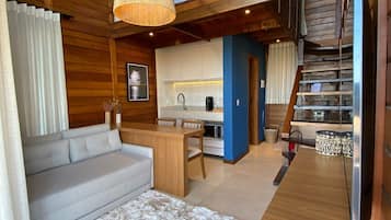 Un intérieur moderne comprenant un canapé, un coin repas, une cuisine et un escalier.
