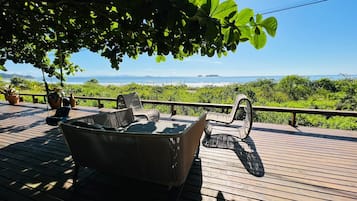 Relax on the deck with a sofa and two chairs, taking in the serene views of the beach and distant island.