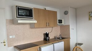 A compact kitchen with wooden cabinets, a microwave, a coffee maker, and a refrigerator. - Floor -1, view ski slopes, jacuzzi, hammam, balcony, parking, tv, 30m², Peyragudes (Germ)