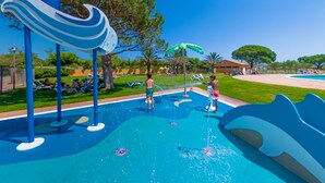 Un parque acuático con toboganes y juegos de agua, rodeado de árboles y una zona de piscina.