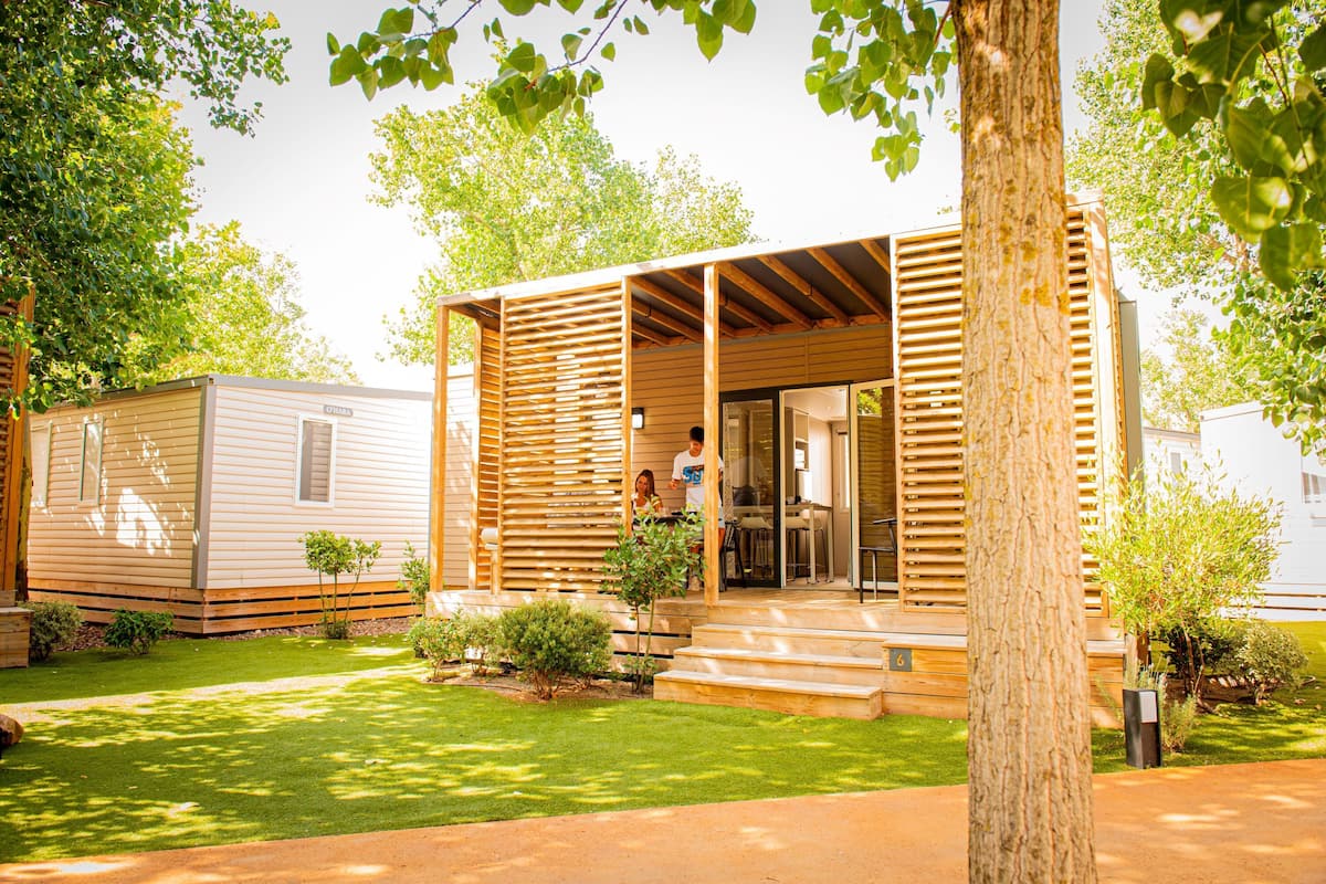 Une maison mobile avec une façade en bois, un petit porche et une pelouse bien entretenue.