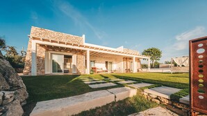 Een modern huis met een stenen gevel, een overdekt terras en een verzorgd gazon.
