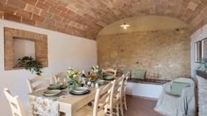 A dining area with a brick ceiling, stone walls, and a rustic wooden table set for four. - Casa La Fenice 8+2, Emma Villas (Pomarance)