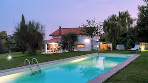 Piscina com uma casa ao fundo.