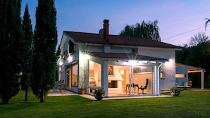 Uma casa de dois andares com um alpendre coberto e um gramado bem cuidado.