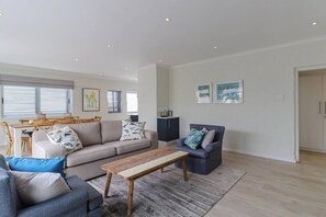 A spacious living area with a sofa, armchair, coffee table, and dining table.