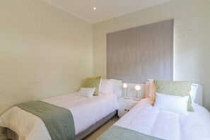 A hotel room with two beds, a nightstand with lights, and a large wall panel.