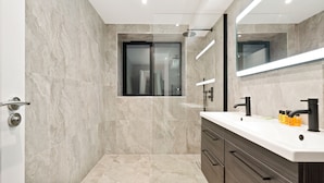 Un baño moderno con un espejo grande, un lavabo blanco y una zona de ducha.