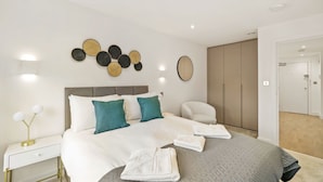 Un dormitorio moderno con una cama grande, mesitas de noche, un espejo y un armario.