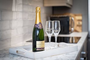A bottle of champagne and two glasses on a marble tray in a kitchen setting. - Modern Flat Minutes from Exmouth Sea Front (Exmouth)