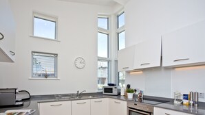 A modern kitchen with white cabinets, a built-in oven, a microwave, and a sink. - 2 bedroom accommodation in Carbis Bay, near St Ives (Carbis Bay, near St Ives)