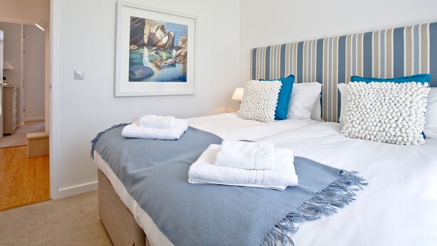 A hotel room with a bed, a painting on the wall, and a striped headboard. - 2 bedroom accommodation in Carbis Bay, near St Ives (Carbis Bay, near St Ives)