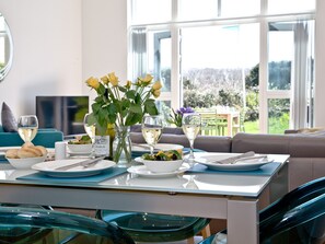 A dining table set with plates, glasses, and a vase of flowers. - 2 bedroom accommodation in Carbis Bay, near St Ives (Carbis Bay, near St Ives)