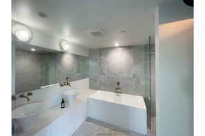 Een bad/douchecombinatie, een haardroger, handdoeken, shampoo