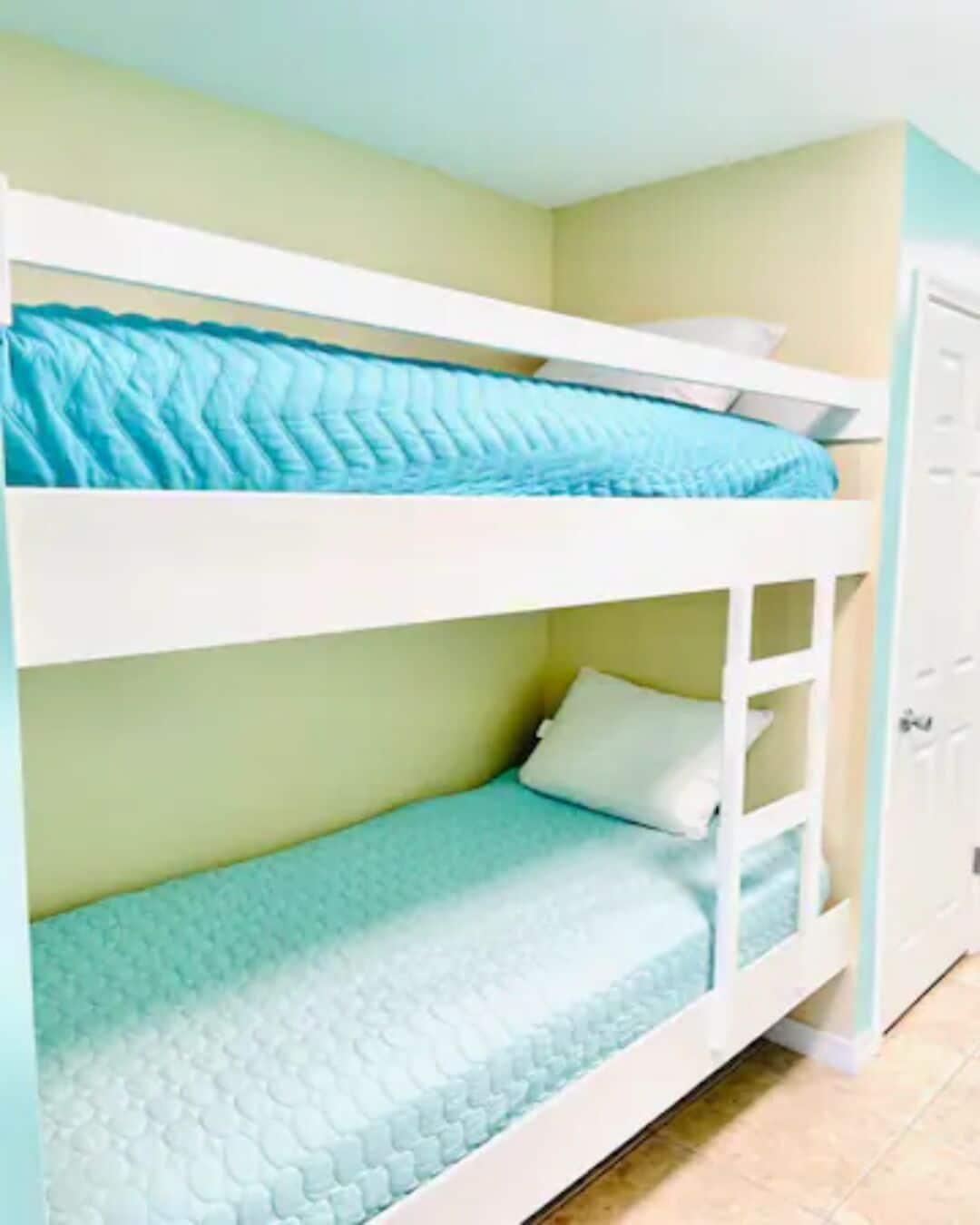 Un letto a castello con materasso blu e testiera bianca.