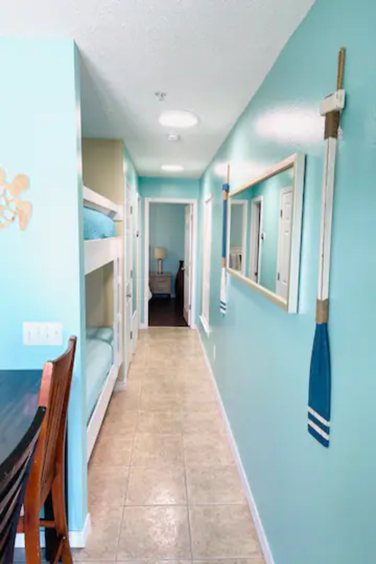 A narrow hallway with bunk beds on one side and a dining area on the other.