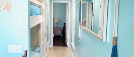 A narrow hallway with bunk beds on one side and a dining area on the other.