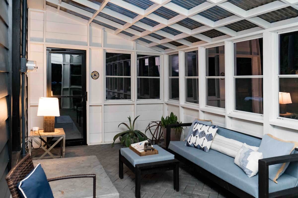 A sunroom with a glass ceiling, a sofa, a table, and a chair.